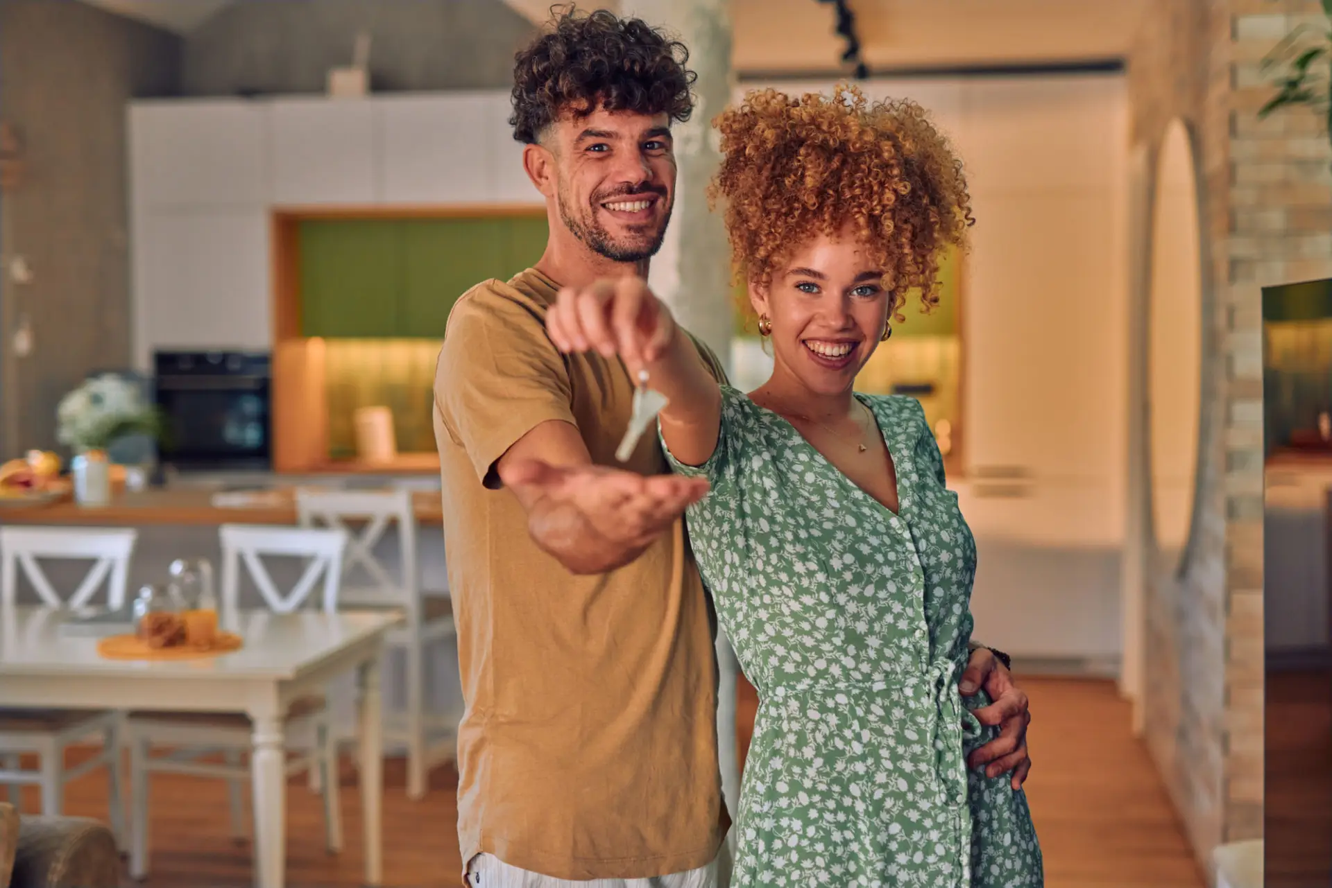First time homebuyers holding keys in front of their new home, representing FHA home loan financing