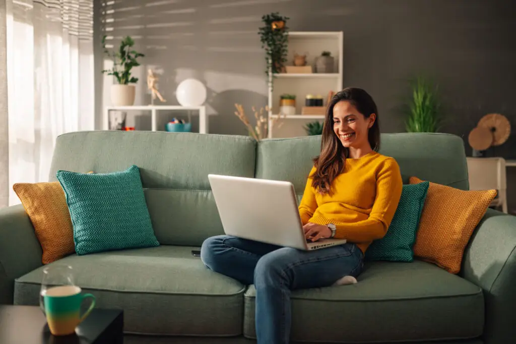 Business owner working on her laptop from the sofa at home