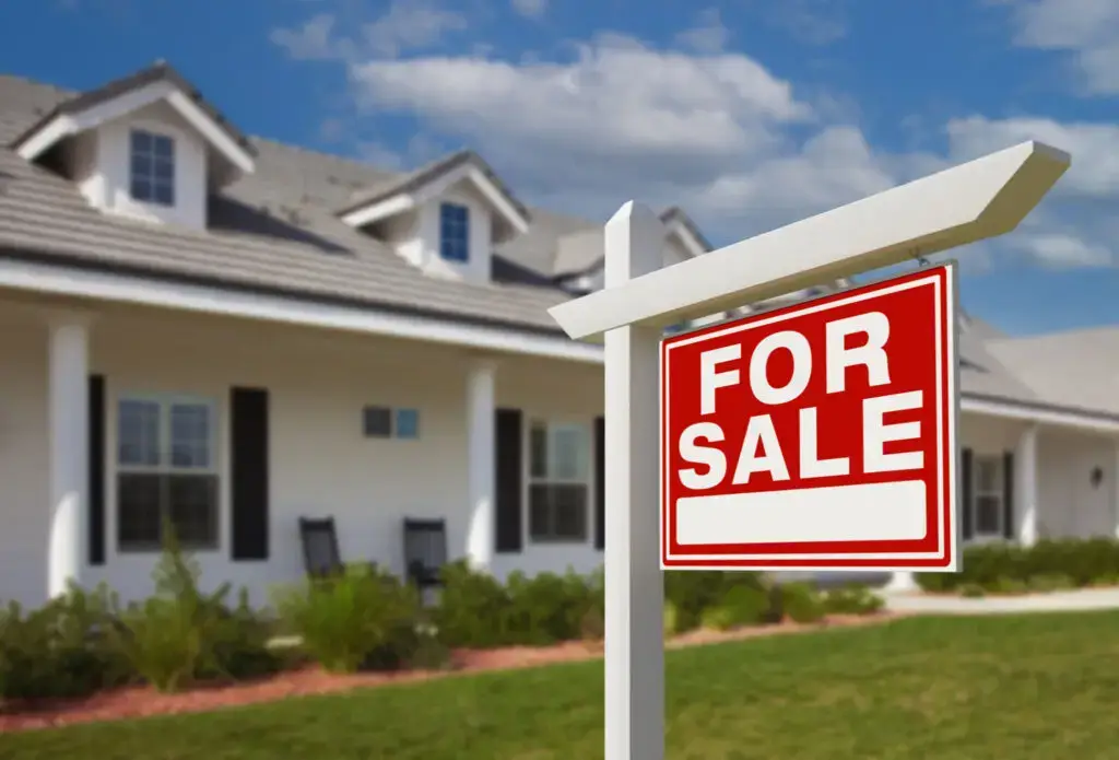 Two story home with a for sale sign on the front lawn