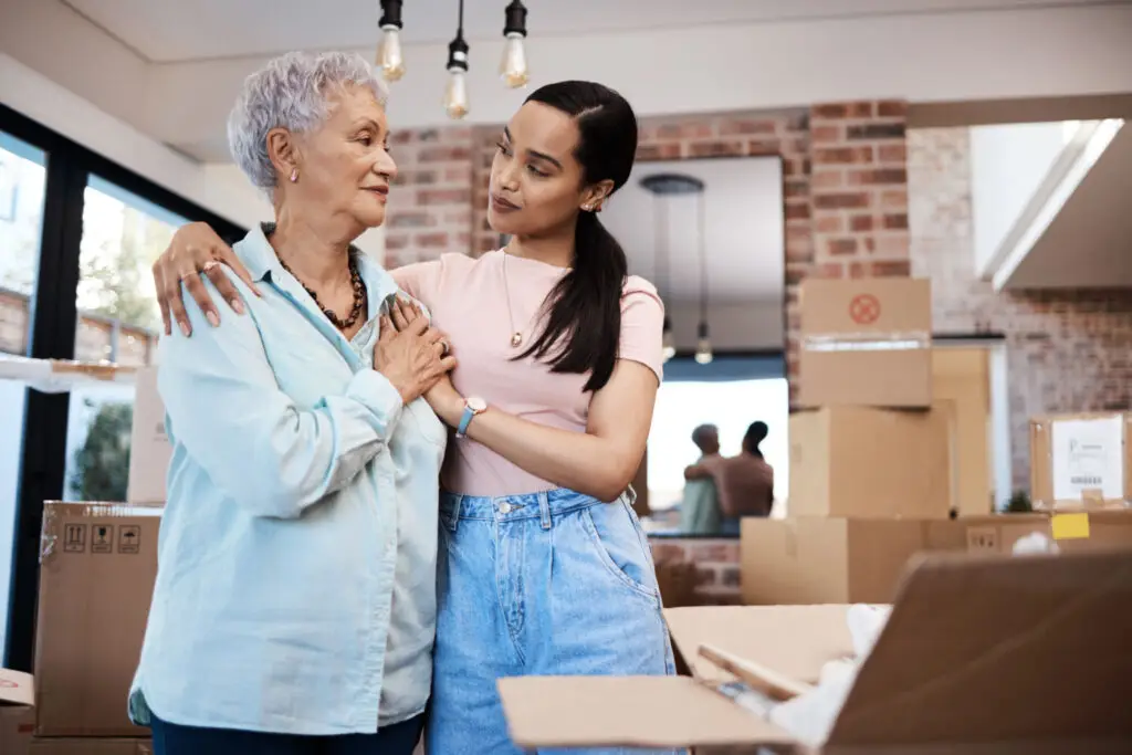 Older woman and her adult daughter packing moving boxes while downsizing