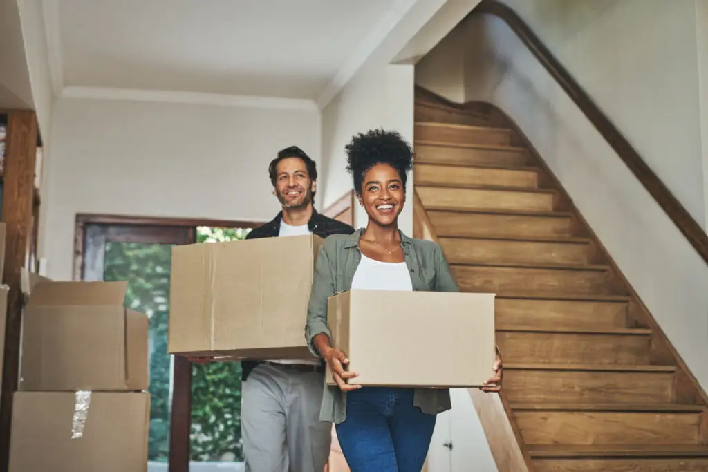Couple carrying moving boxes into their first home